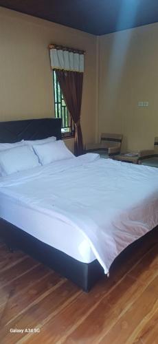 a large white bed in a bedroom with a wooden floor at BougenVille in Labu Pumi