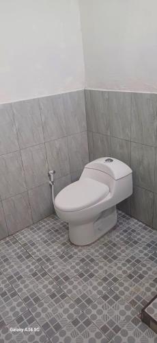 a toilet in a bathroom with a tiled floor at BougenVille in Labu Pumi