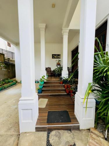a hallway of a house with white columns and plants at Akshi Hostel in Kandy