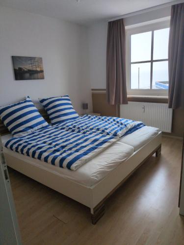 a bed with blue and white striped pillows in a bedroom at Fabelhaft am Meer in Timmendorfer Strand