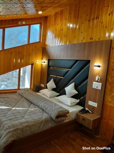 a bedroom with a large bed with wooden walls and windows at Hotel Pahalgam view in Pahalgām