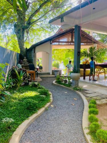 a garden with a gravel path and a patio at Eagle Point Riverside Stay in Weligama