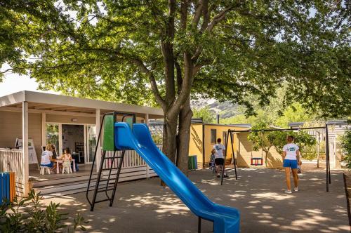 a playground with a blue slide in front of a tree at Camping Baska in Krk