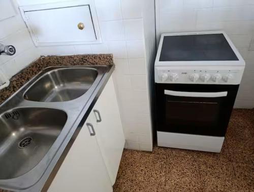 a kitchen with a sink and a stove at Apartamento con vistas al mar! Comaruga in La Playa