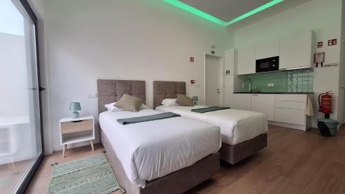 a bedroom with two beds and a kitchen with at AzoreanStar Accommodations in Ponta Delgada