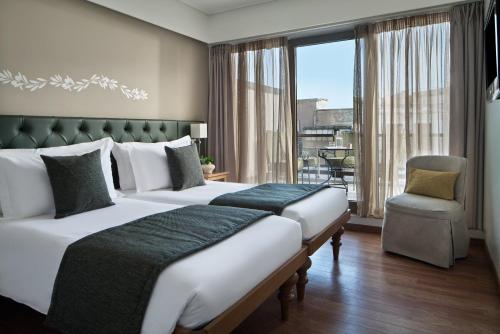 een hotelkamer met twee bedden en een groot raam bij Titania Hotel in Athene