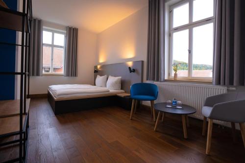 a hotel room with a bed and a blue chair at Gutshof Vogt in Geismar