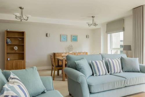 a living room with a blue couch and a table at Isle be Back - Harbour front Views from Balconies in Poole