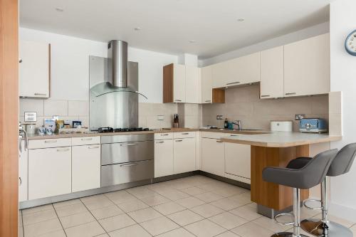 a kitchen with white cabinets and a table and chairs at Isle be Back - Harbour front Views from Balconies in Poole