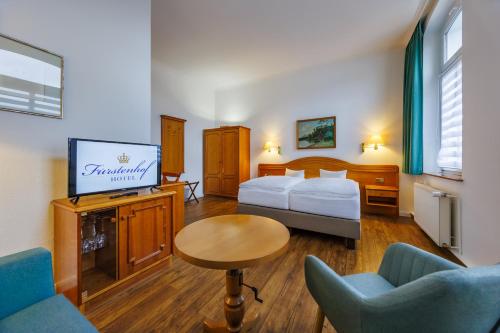 a hotel room with a bed and a tv at Hotel Fürstenhof in Rathenow