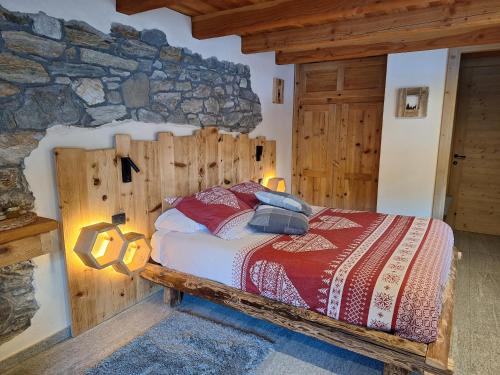 a bedroom with a bed with a stone wall at Le Camere di Naturalys - ospitalità in azienda agricola in Gaby