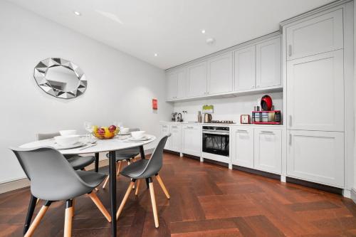 a kitchen with white cabinets and a table and chairs at 2 Bed Lux Apartments near Central London FREE WIFI by City Stay Aparts London in London