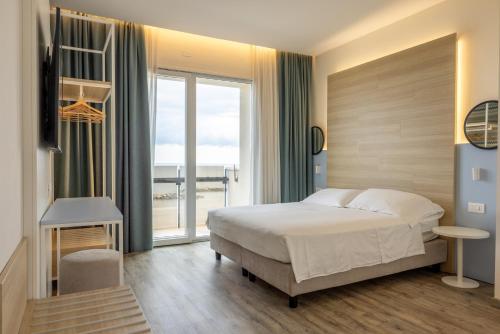a bedroom with a bed and a large window at Hotel Baia in Rimini