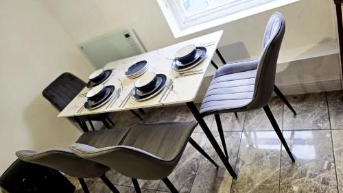 a table with three chairs and a plate and spoon and fork at City Centre 2 Bed 2 Bath 5 guest with Cheapest overnight Car park Entrepreneur Stays in Leicester