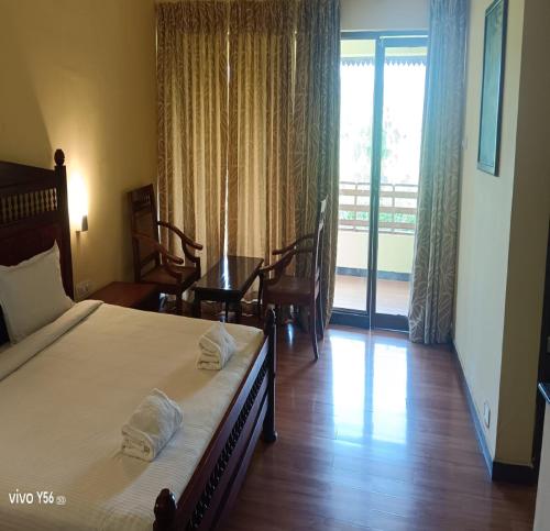 a bedroom with a bed and a table and a balcony at Manor Backwater Resort in Kumarakom