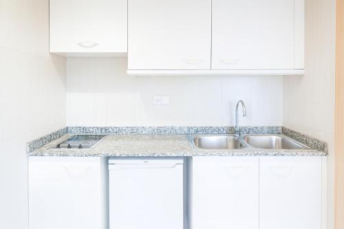a white kitchen with a sink and white cabinets at Apartamentos Vistasol in Magaluf