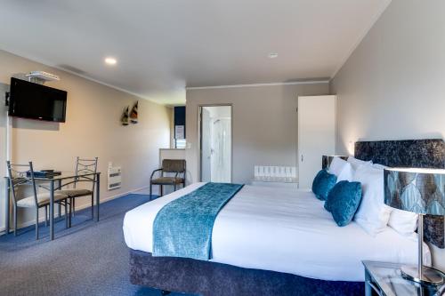 a hotel room with a large bed and a table at Portmans Motor Lodge in Hastings