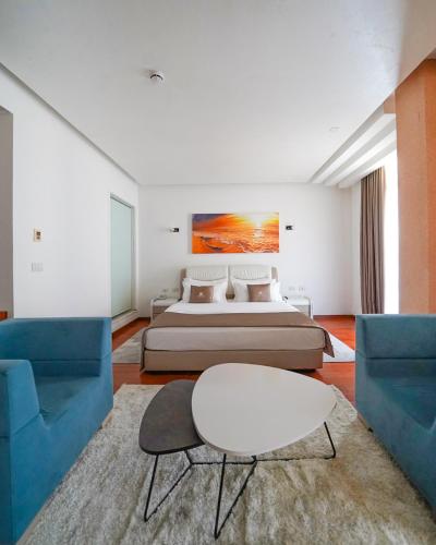 a bedroom with a bed and two blue chairs at Rafaelo Deluxe Hotel & Spa Shengjin in Shëngjin