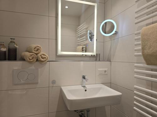 a white bathroom with a sink and a mirror at Herzmuschel in Norderney