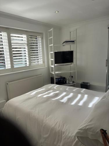 a bedroom with a large white bed and a flat screen tv at Mayfield guest rooms in Bromley