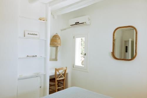 a white bedroom with a mirror and a chair at Villa Riza in Apróvaton