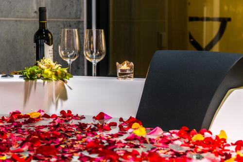 a table topped with wine glasses and a vase filled with flowers at Aguila Hotel Jeju Oceano Suite in Jeju