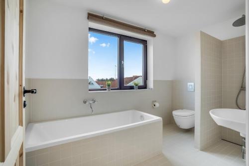 a bathroom with a tub and a toilet and a window at God Plads Og God Beliggenhed I Løkkenshus in Løkken