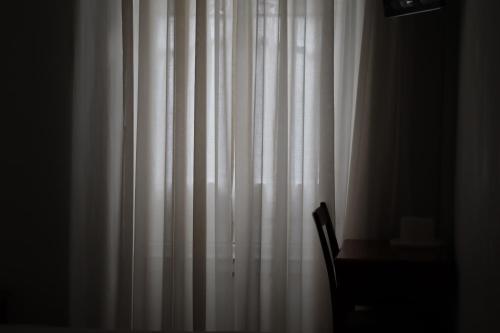 a white curtain in a room with a chair at Hotel Peninsular- Porto in Porto
