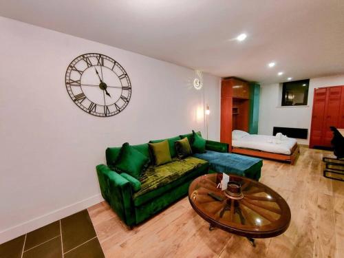 a living room with a green couch and a clock on the wall at Milliaux - Bail Partner in Auxerre