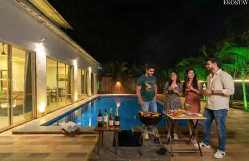a group of people standing in front of a swimming pool at Ekostay - Crown Villa in Alibaug