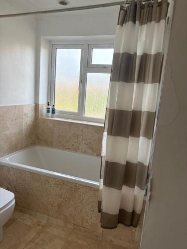 a bathroom with a bath tub and a window at Mayfield guest rooms in Bromley