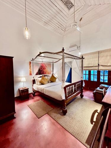 a bedroom with a canopy bed and a couch at Colonial Boutique Villa Kandy in Kandy