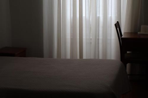 una camera da letto con un letto, una scrivania e una tenda bianca di Hotel Peninsular- Porto a Porto