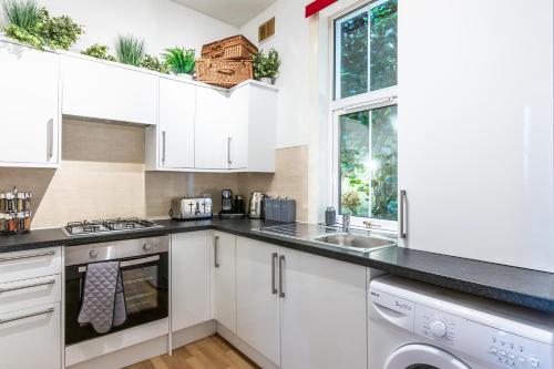 a kitchen with white cabinets and a sink at Lamont Cottage in Inverness