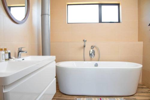 a bathroom with a large white tub next to a sink at Nkandla Resort in Bulawayo