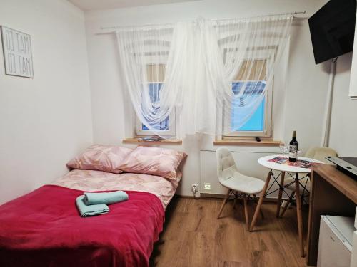 a small bedroom with a bed with a red blanket at Dzień dobry w Szczytnej in Szczytna