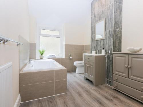 a bathroom with a tub and a sink and a toilet at 3 Bay View Terrace in Llandudno