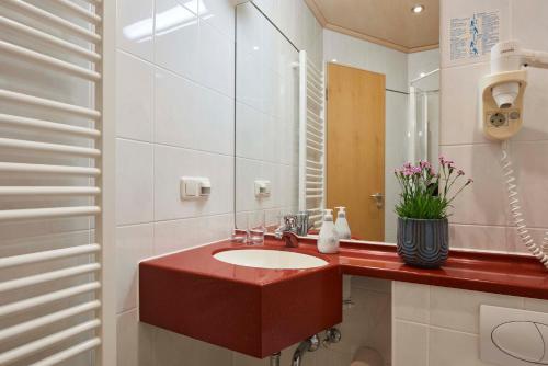 a bathroom with a red sink and a mirror at Gasthaus Alter Wirt in Oberneuching