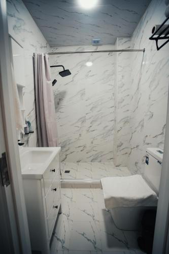a white bathroom with a shower and a toilet at Bog’ishamol Hotel Urgut in Min-Bulak