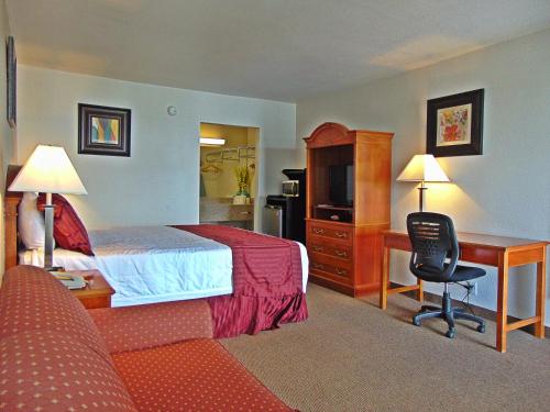 a hotel room with a bed and a desk at Ramada by Wyndham Kingman in Kingman