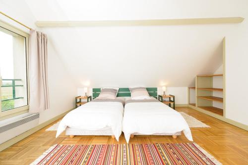 two beds in a white room with a rug at Le Logis d Orgeval in Orgeval