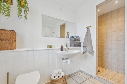 a white bathroom with a sink and a mirror at Holstvej 21 Holiday Home For 12 Guests With An Extra Bonus in Blokhus