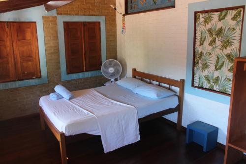 a small bedroom with a bed with a fan at Casa Blanka 2010 - Eco Surf Guest House in Itacaré