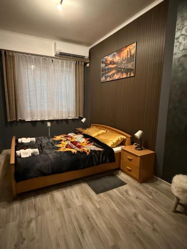 a bedroom with a bed and a table and a window at Vila Alexandra 2025 in Bačka Topola