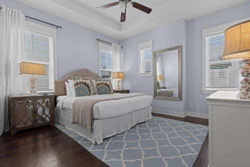 a bedroom with a bed with a ceiling fan and windows at Prominence 30A - Coastal Cottage in Panama City Beach