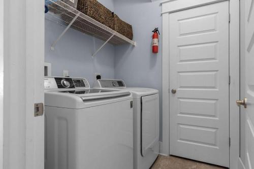 a white laundry room with a washing machine and a door at Prominence 30A - Coastal Cottage in Panama City Beach