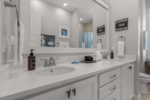 a white bathroom with a sink and a mirror at Sea Haven At Prominence in Watersound Beach