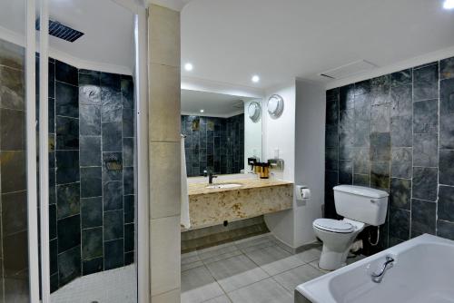 a bathroom with a toilet and a sink at Pilanesberg Hotel in Boshoek