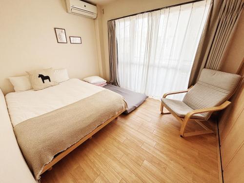a bedroom with a bed and a chair and a window at 時旅ー大正 in Osaka