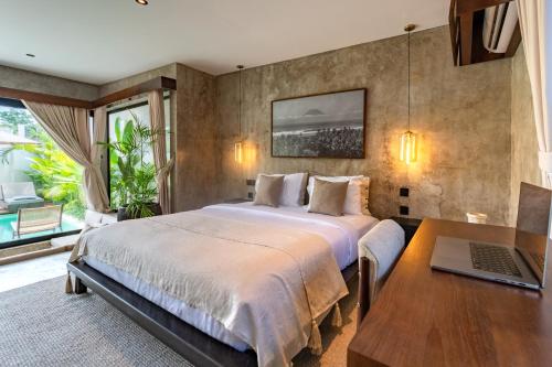 a bedroom with a bed and a laptop on a table at Atol Villas in Uluwatu